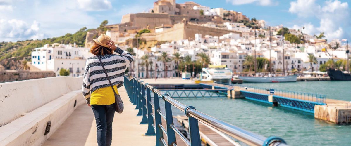 Woman strolling through Dalt Vila with Ibiza in the background